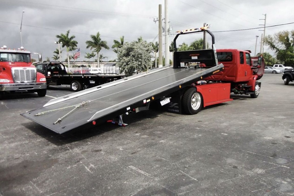 Red flatbed tow truck with extended platform for safe vehicle transport