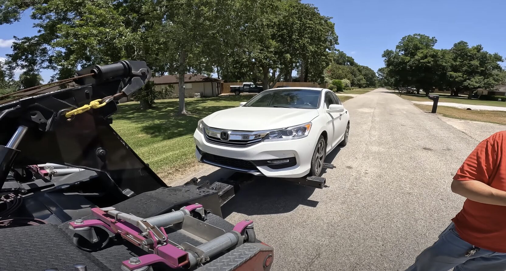 Emergency towing service with flatbed truck loading sedan vehicle