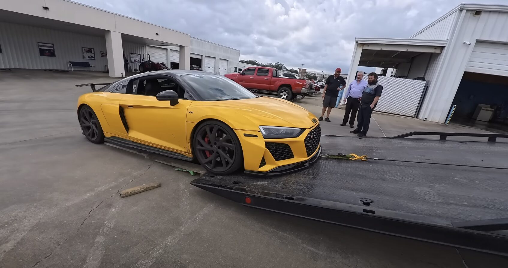 Yellow sports car being loaded onto professional flatbed tow truck
