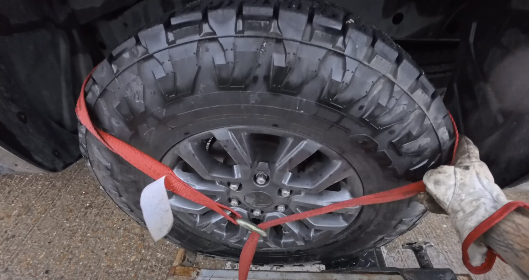 Roadside assistance technician securing vehicle tire with emergency straps